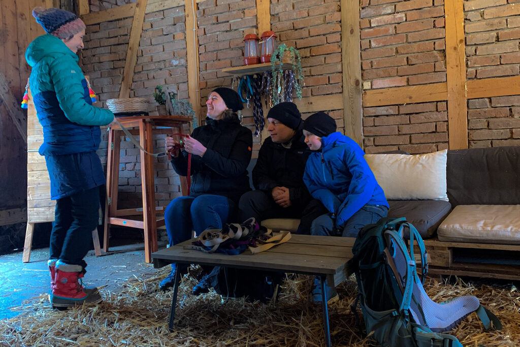 drei Menschen schauen sich eine Leine zur Alpaka Wanderung an